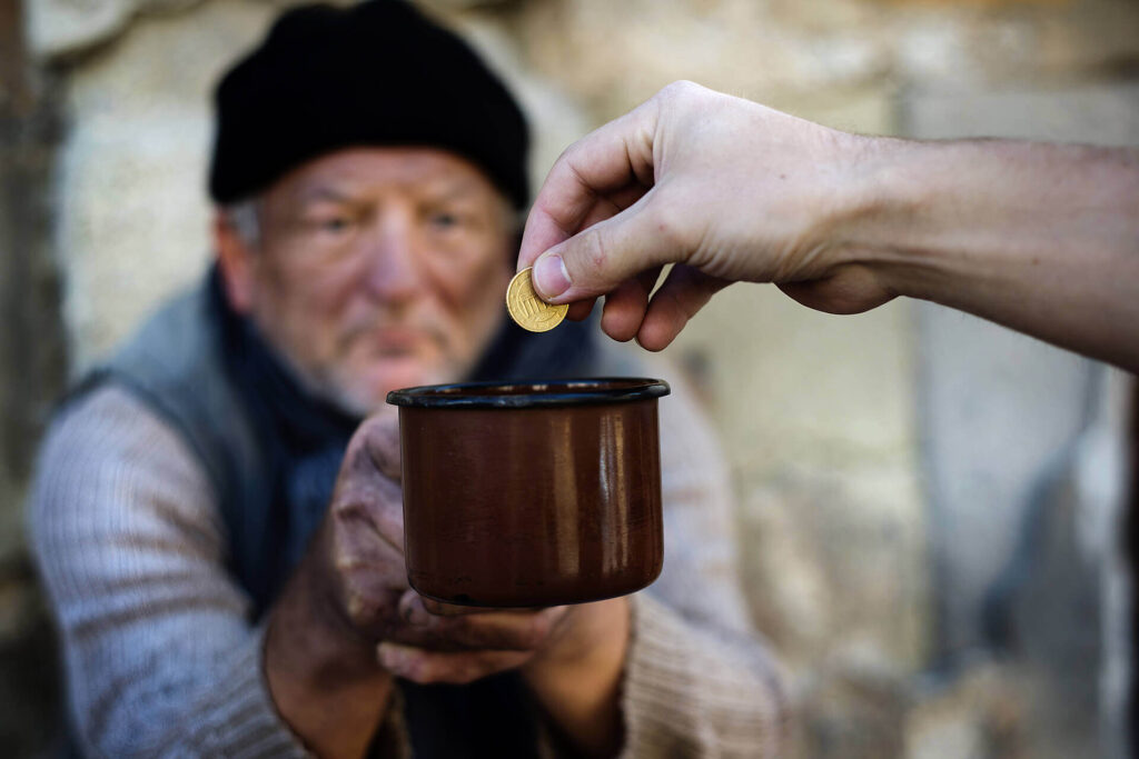 Hand placing coin into a begging bowl.
