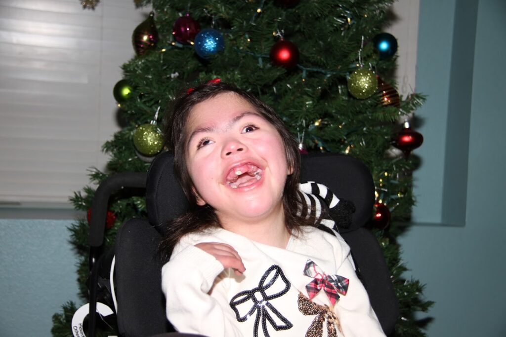 Child smiling in front of a Christmas tree.