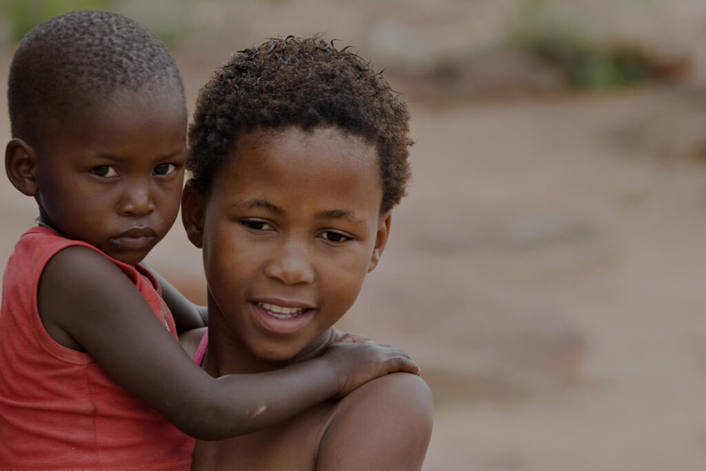 Two children smiling and embracing outdoors.