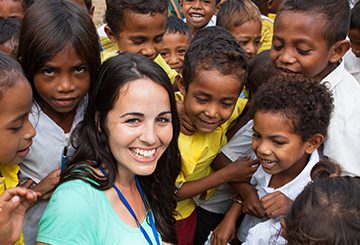 Smiling woman surrounded by cheerful children.